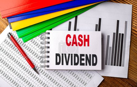 CASH DIVIDEND text on notebook with folder on a chart.