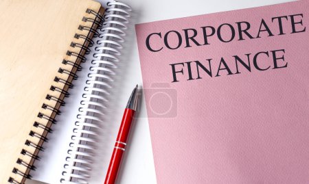 CORPORATE FINANCE text on a pink paper with notebooks . 