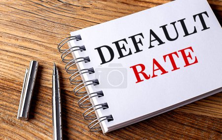 DEFAULT RATE text on a notebook on wooden background . 