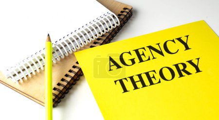 AGENCY THEORY text on a yellow paper with notebooks. 