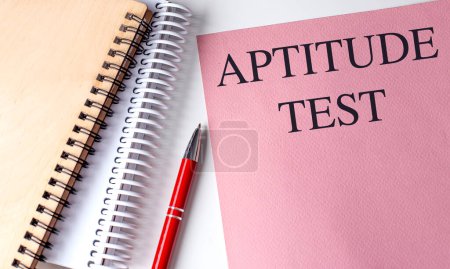 APTITUD TEST texto sobre papel rosa con cuadernos . 