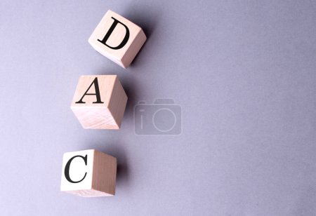 DAC-Wort auf einem Holzblock auf grauem Hintergrund 