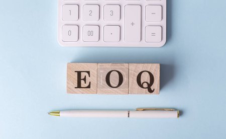EOQ palabra en un bloque de madera con pluma y calculadora sobre fondo azul . 