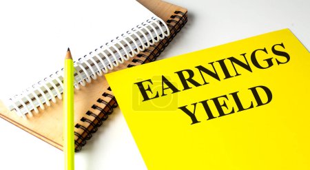 EARNINGS YIELD text on a yellow paper with notebooks. 