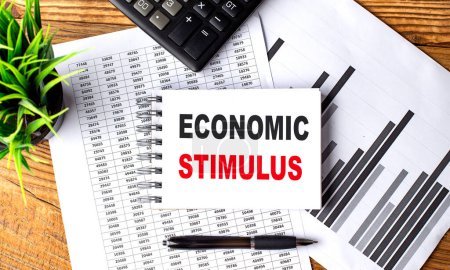 ECONOMIC STIMULUS text on a notebook on chart with calculator and pen . 