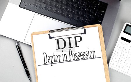 DIP- DEBTOR IN POSSESSION word on a clipboard on laptop with calculator and pen . 