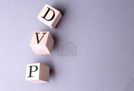 Palabra DVP en un bloque de madera sobre fondo gris . 