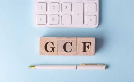 Palabra GCF en un bloque de madera con pluma y calculadora sobre fondo azul . 