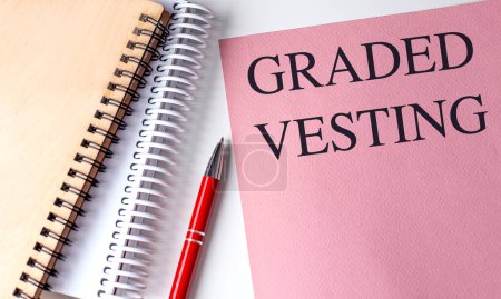 GRADED VESTING text on a pink paper with notebooks . 