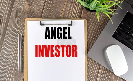 ANGEL INVESTOR text on a clipboard paper with laptop, mouse and pen . 