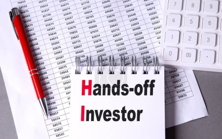 HANDS-OFF INVESTOR text on a notebook with chart , pen and calculator.