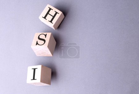 HSI-Wort auf einem Holzblock auf grauem Hintergrund 