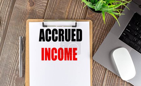 ACCRUED INCOME text on a clipboard paper with laptop, mouse and pen . 