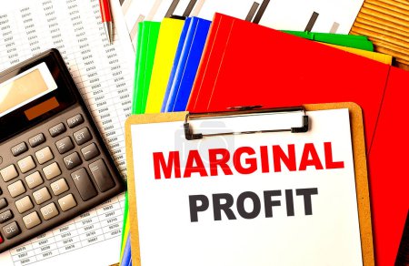 MARGINAL PROFIT text on a clipboard with calculator and color folder 