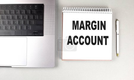 MARGIN ACCOUNT text on a notebook with laptop and pen . 