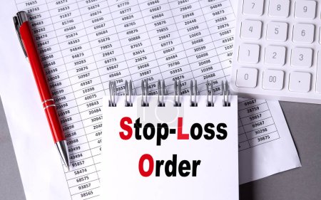 STOP-LOSS ORDER text on a notebook with chart , pen and calculator. 