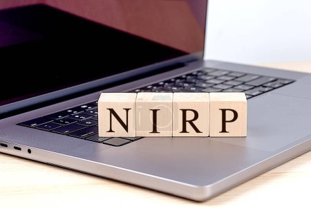 NIRP Wort auf einem Holzklotz auf einem Laptop, Geschäftskonzept. 