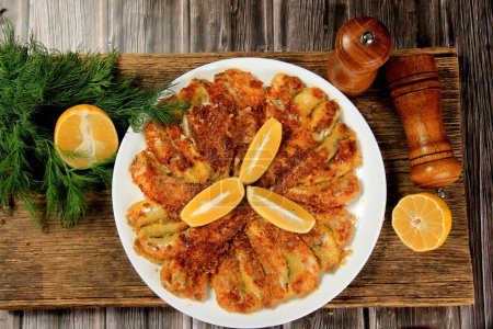 Foto de Pescado frito en un plato, decorado con rodajas de limón - Imagen libre de derechos