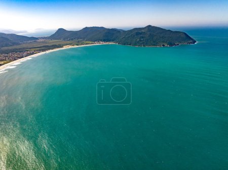 Coastline with beach, mountains and blue ocean with waves in Brazil. Aerial view of Saquinho beach. Florianopolis Santa Catarina. SC