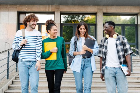 Téléchargez les photos : Heureux étudiants marchant ensemble sur le campus universitaire, bavardant et riant à l'extérieur après les cours - en image libre de droit