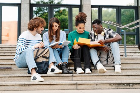 Photo for Young students sitting on University stairs. College friends studying together after class - Royalty Free Image