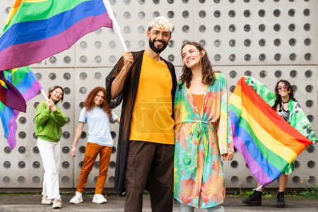 Group of gay people holding rainbow flags, smiling and happy at Lgbt festival with smiles on their faces, enjoying a fun public event. The colorful flags represent happiness and diversity