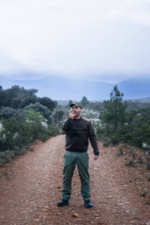 Mann spricht mit Walkie-Talkie-Radio zu Fuß auf dem Nationalpark Reserve - Forest Ranger