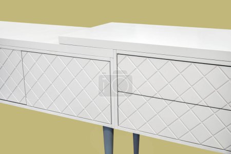 White dressing table with milled facades in shape of rhombs isolated on yellow background. Modern domestic furniture with stylish design for bedroom