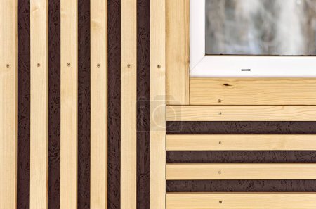 Building wall and window decorated with stylish wooden slats made of thin light planks on house terrace extreme close view