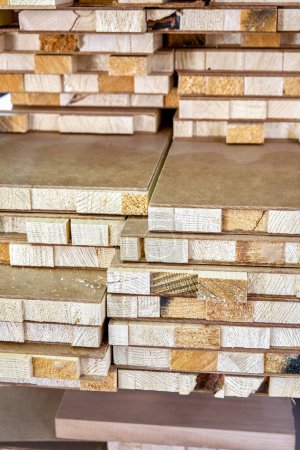 Stack of block boards made of wooden planks and MDF material in carpentry warehouse. Workpieces of doors in manufacturing plant workshop