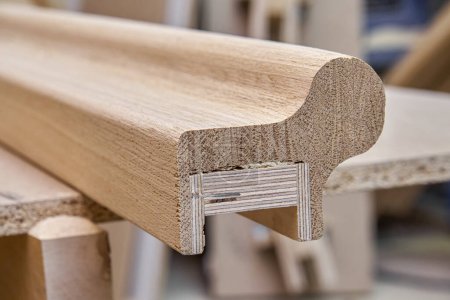 Barandilla de escalera de madera de forma irregular hecha de tablones de roble y madera contrachapada en primer plano de la mesa. Detalle de valla de escaleras en taller de carpintería