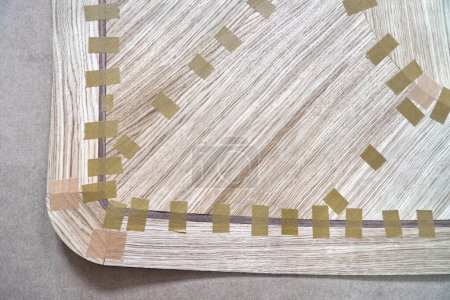 Placage articulé avec du ruban adhésif dans la toile pour le dessus de table de la table à manger avec motif géométrique sur établi dans l'atelier vue de près supérieure