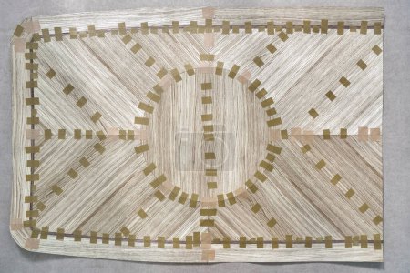 Chapa unida con cinta adhesiva en un gran lienzo para mesa de mesa de comedor con patrón geométrico en el banco de trabajo en la vista superior del taller