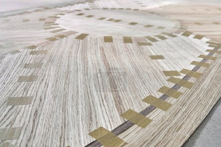 Jointed veneer with tape for table top of dining table with geometric pattern on workbench in workshop closeup