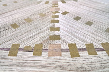 Fugenfurnier mit Klebeband für Tischplatte des Esstisches mit geometrischem Muster auf Werkbank in Werkstattnahaufnahme