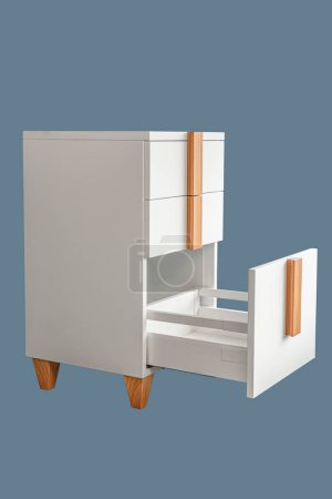 Stilvolle weiße Bürokommode mit Holzgriffen und Beinen mit offenen leeren Schubladen isoliert auf blauem Hintergrund. Komfortable Möbel für Haus und Büro
