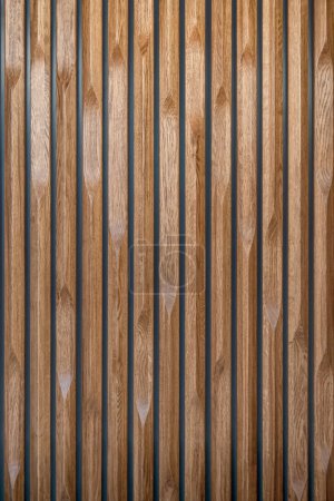 Téléchargez les photos : Panneau en bois décoratif en chêne massif de lattes verticales rainurées avec des motifs de bord variés, créant une surface texturée comme fond - en image libre de droit