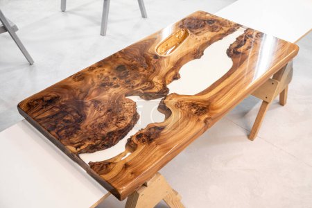 Plateau de table en dalle d'orme de bord vivant avec rivière centrale en résine époxyde sur les sawhorses dans un atelier professionnel
