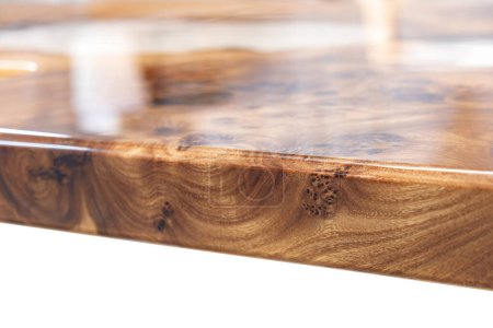 Borde vivo olmo burl mesa superior con resina epoxi central río sobre fondo blanco, la combinación de madera natural con un material sintético vista cercana