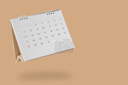 White paper desk calendar flipping page isolated on brown background