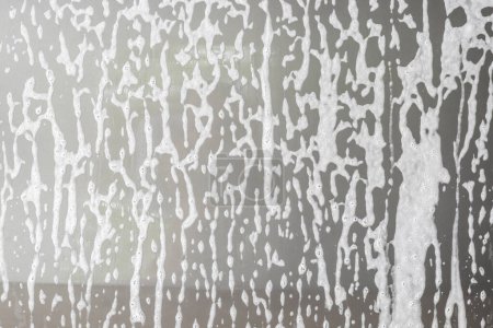 Autoreinigung und Waschen mit Schaumseife auf dem grauen Auto-Hintergrund