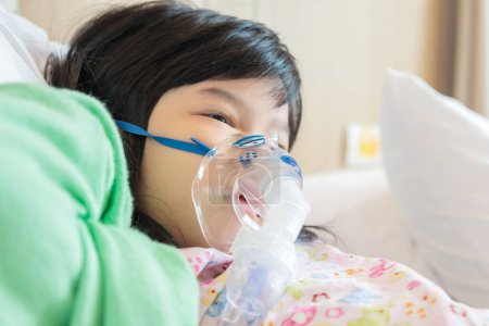 Sick little asian girl inhalation with nebulizer for respiratory treatment
