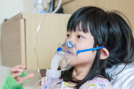 Sick little asian girl inhalation with nebulizer for respiratory treatment