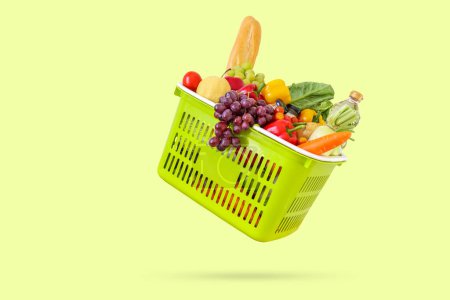 Fresh fruits and vegetables grocery product in green shopping basket isolated on green background