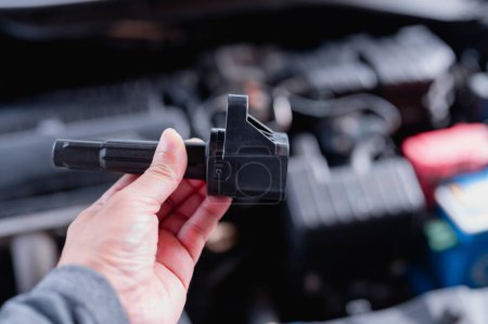 Le technicien automobile inspecte la bobine d'allumage pendant l'entretien de la voiture, assurant ainsi les performances optimales du moteur.