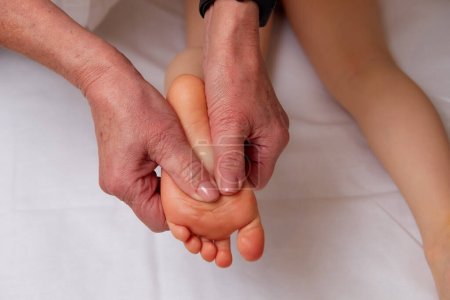 Photo for Closeup of hands of professional doctor performing pediatric foot massage for improve blood circulation in child body - Royalty Free Image