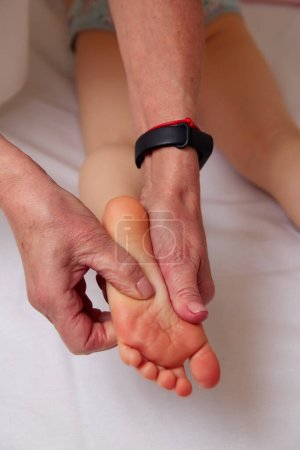Photo for Closeup of small children foot in hands of professional masseuse during reflexology massage. Complementary therapy concept - Royalty Free Image