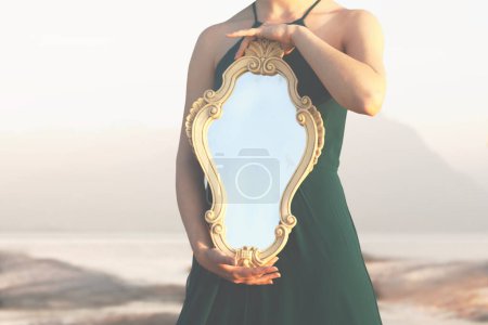 Téléchargez les photos : Femme tenant un miroir magique qui reflète la lumière du soleil ; concept abstrait - en image libre de droit