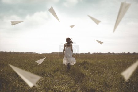 Foto de Vuelo surrealista de aviones de papel que rodean a una mujer corriendo al aire libre - Imagen libre de derechos
