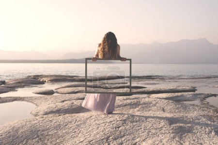 Téléchargez les photos : Femme tenant un cadre qui reflète survraiment le paysage, concept de porte à la liberté - en image libre de droit